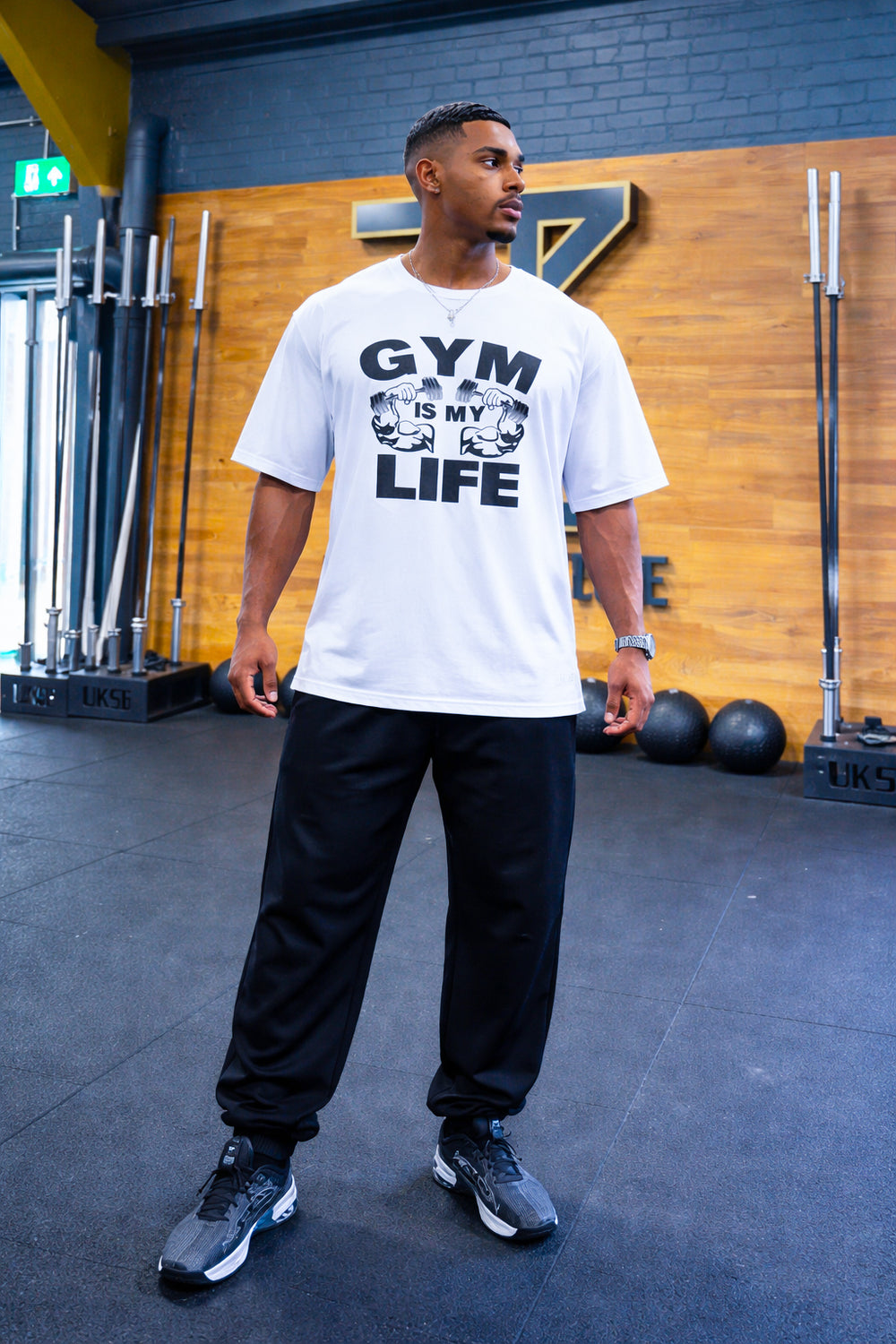 موديل يرتدي تيشيرت GYM IS MY LIFE الأبيض داخل النادي الرياضي