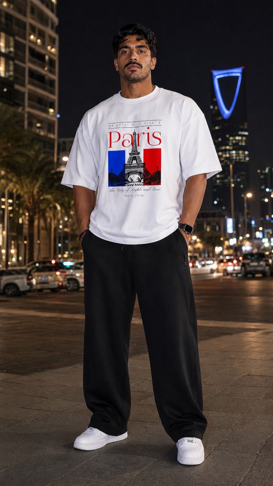 موديل يرتدي تيشيرت PARIS الأبيض مع بنطال أسود واسع في الرياض